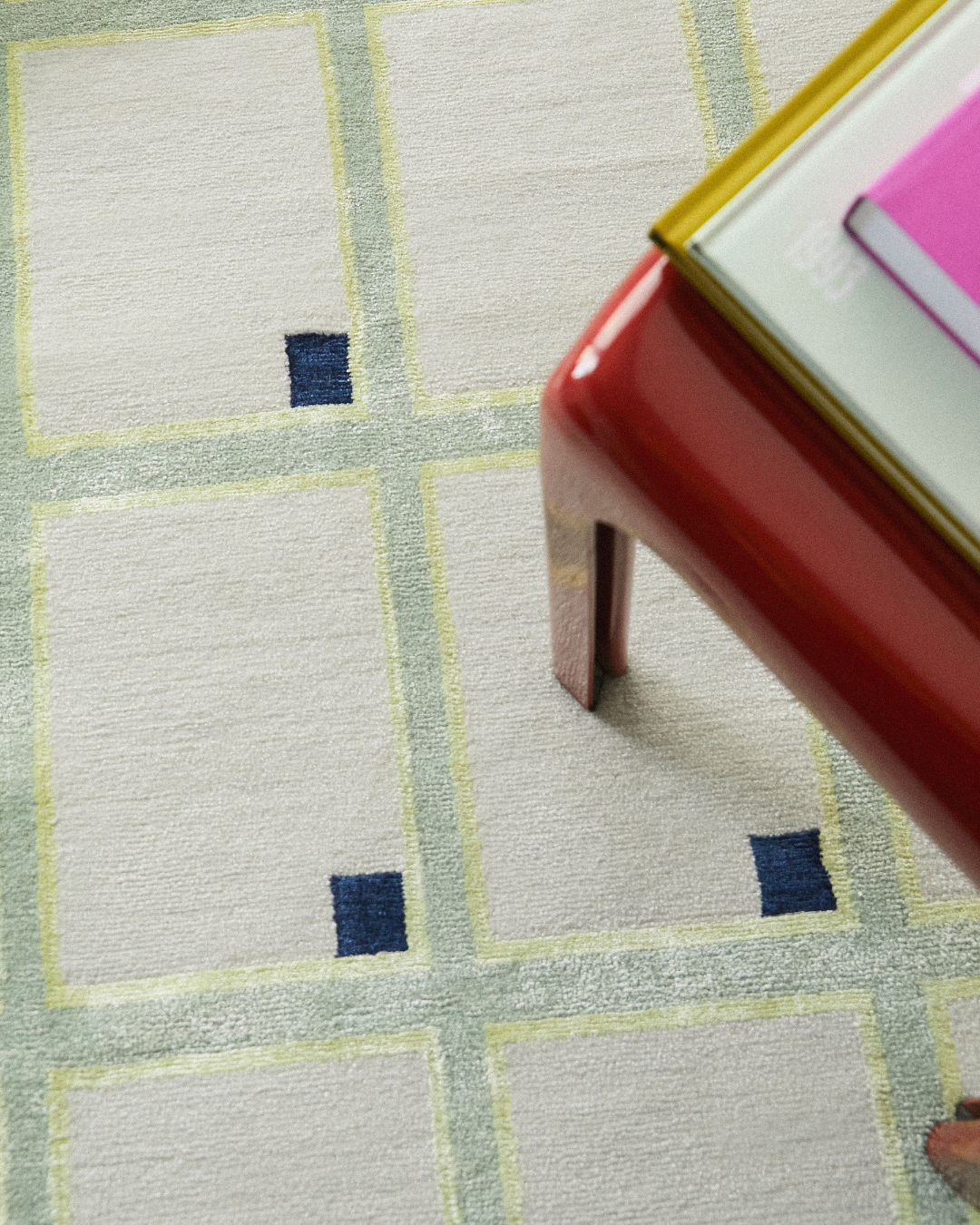 Close-up of the intricate geometric patterns, in pale yellow and navy blue,  on a pale green hand-knotted, limited-edition rug. 