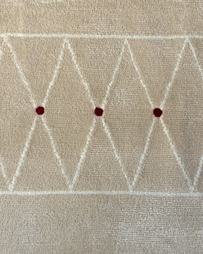 Detail of the Jacques rug, Edition 03: ivory treillage band with three deep crimson points on an oatmeal ground