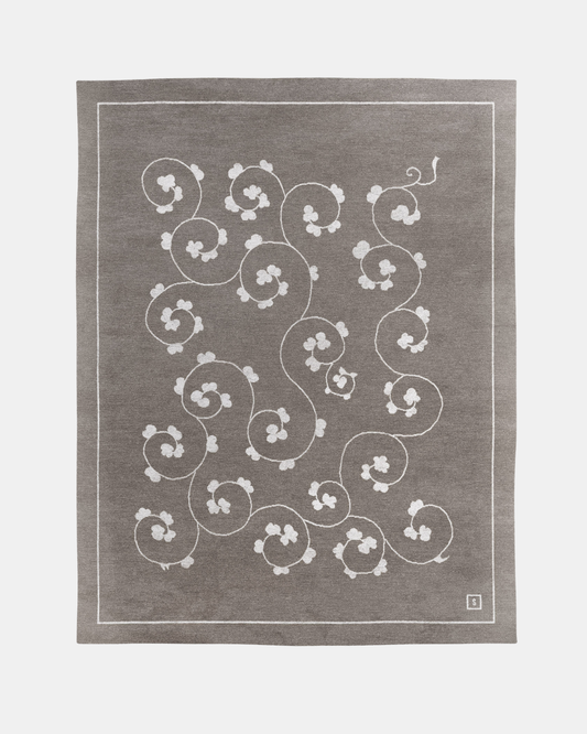 Jardin rug, Edition 03: ivory rinceau scroll carrying small blossoms across a warm mink grey ground, hand-knotted in wool and bamboo silk