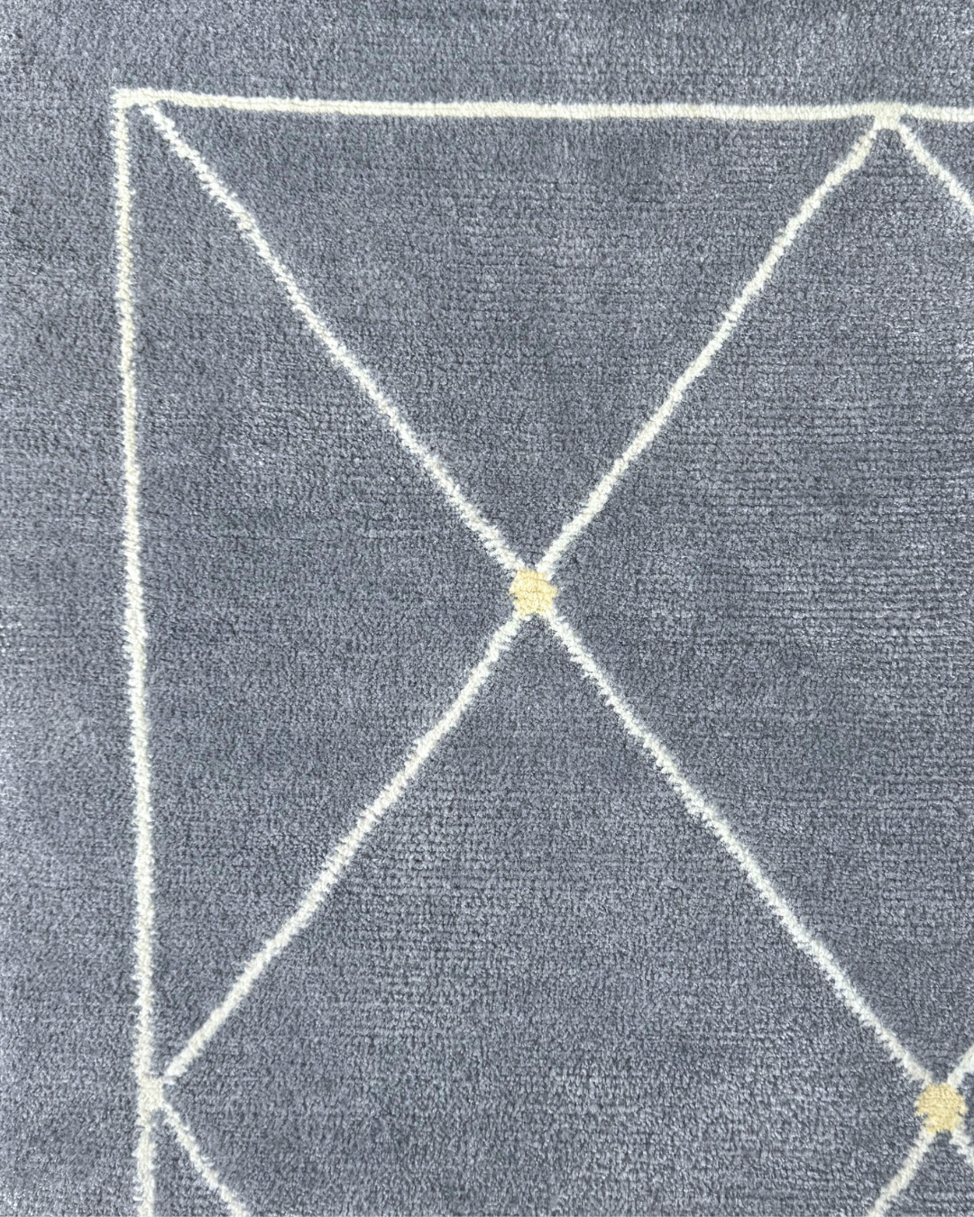 Detail of the Serge rug, Edition 03: white lattice with a pale gold knot at the intersection, on a blue-grey ground
