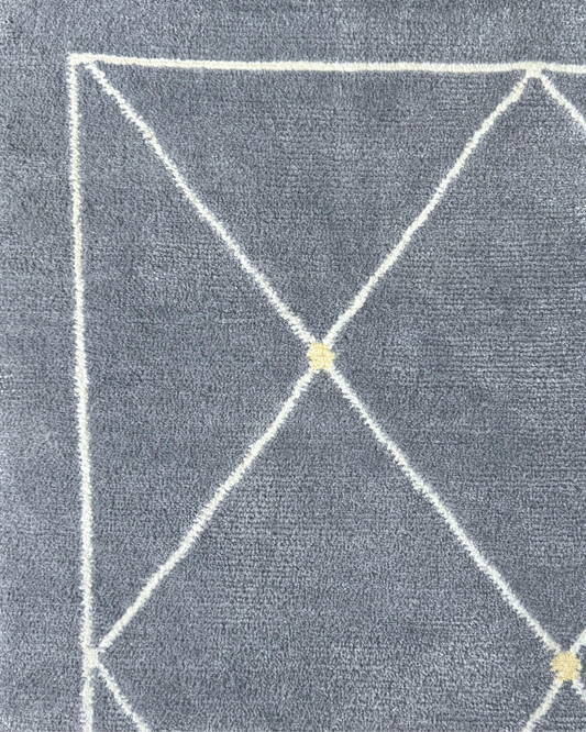 Detail of the Serge rug, Edition 03: pale gold point at the crossing of an ivory lattice on a blue-grey ground